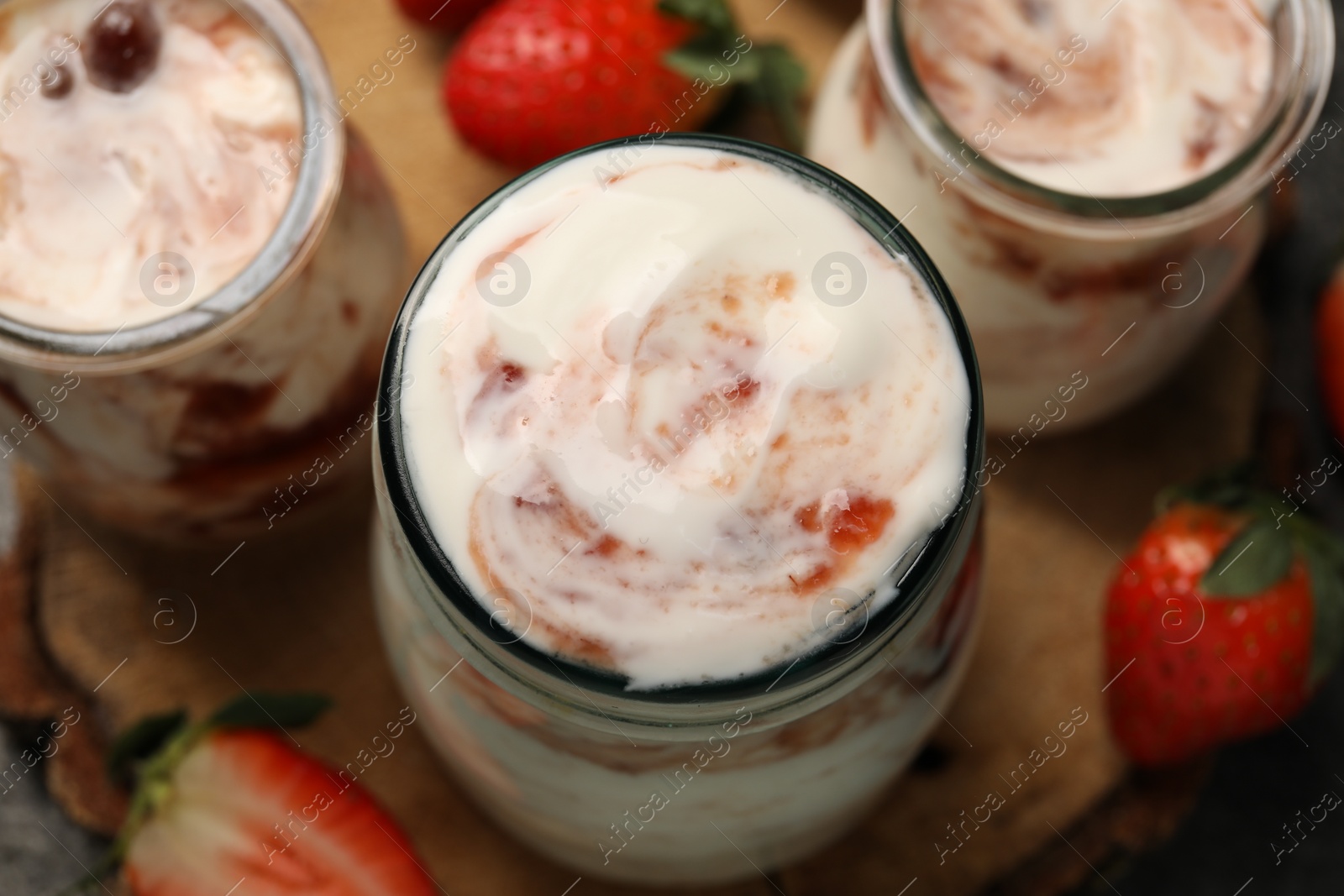 Photo of Tasty yoghurt with jam and strawberries on table, above view