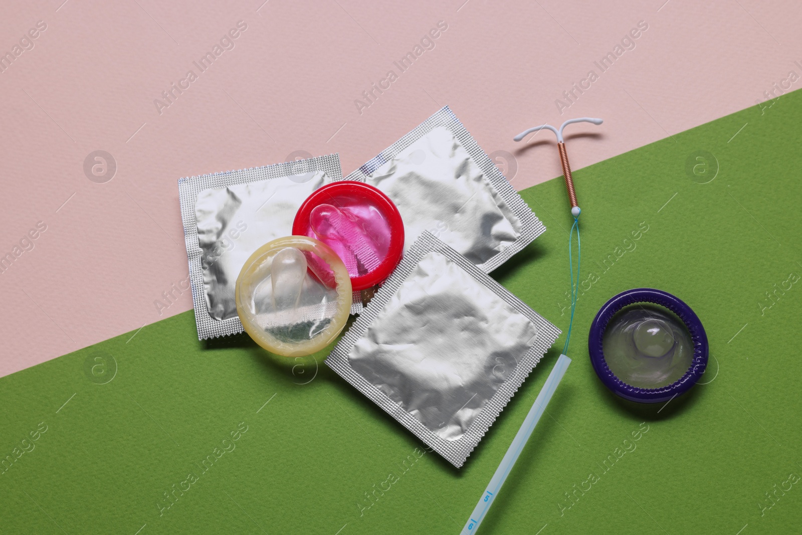 Photo of Condoms and intrauterine device on color background, flat lay. Choosing method of contraception