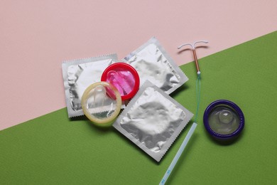 Condoms and intrauterine device on color background, flat lay. Choosing method of contraception