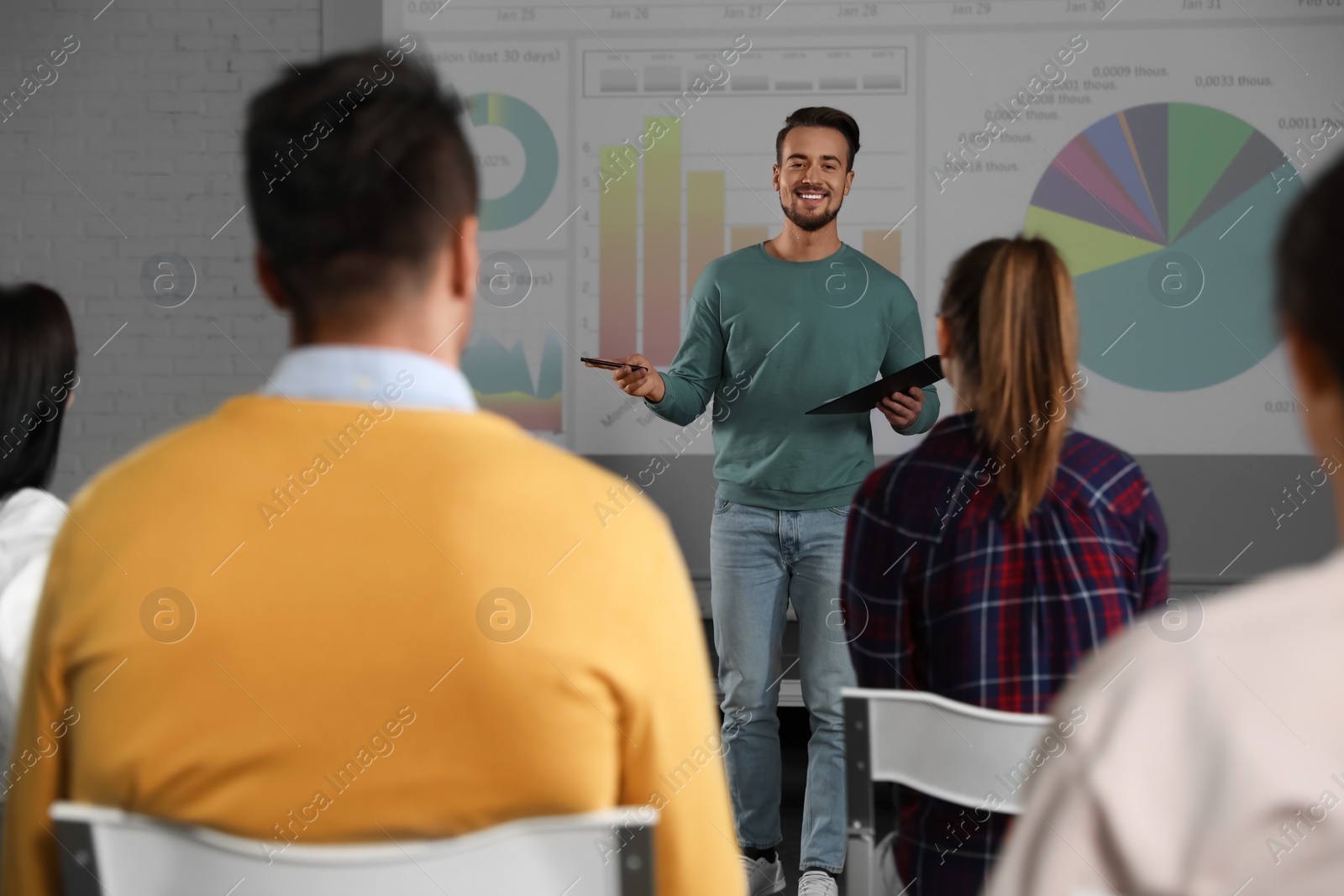 Photo of Male business trainer giving lecture in conference room with projection screen