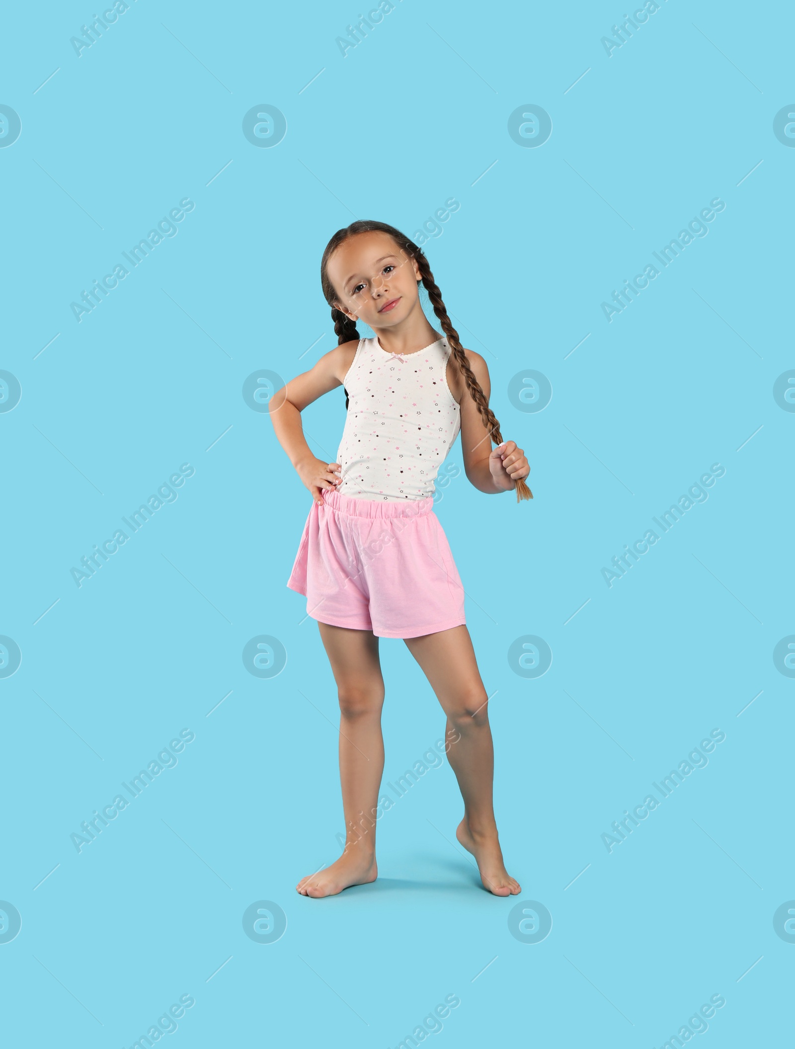 Photo of Cute girl wearing pajamas on light blue background