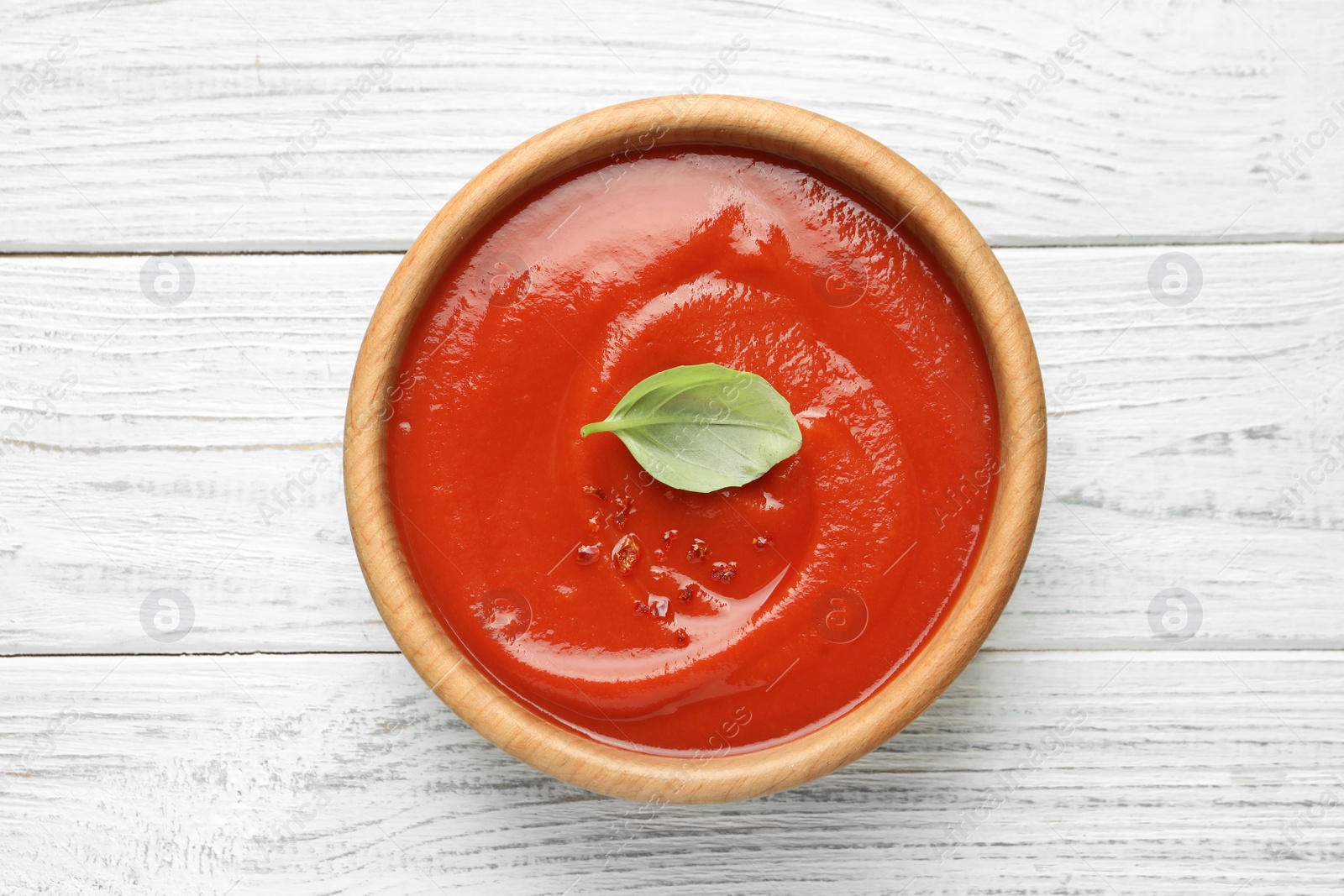 Photo of Bowl with fresh homemade tomato soup on wooden background, top view