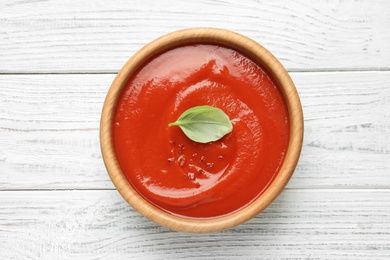 Bowl with fresh homemade tomato soup on wooden background, top view