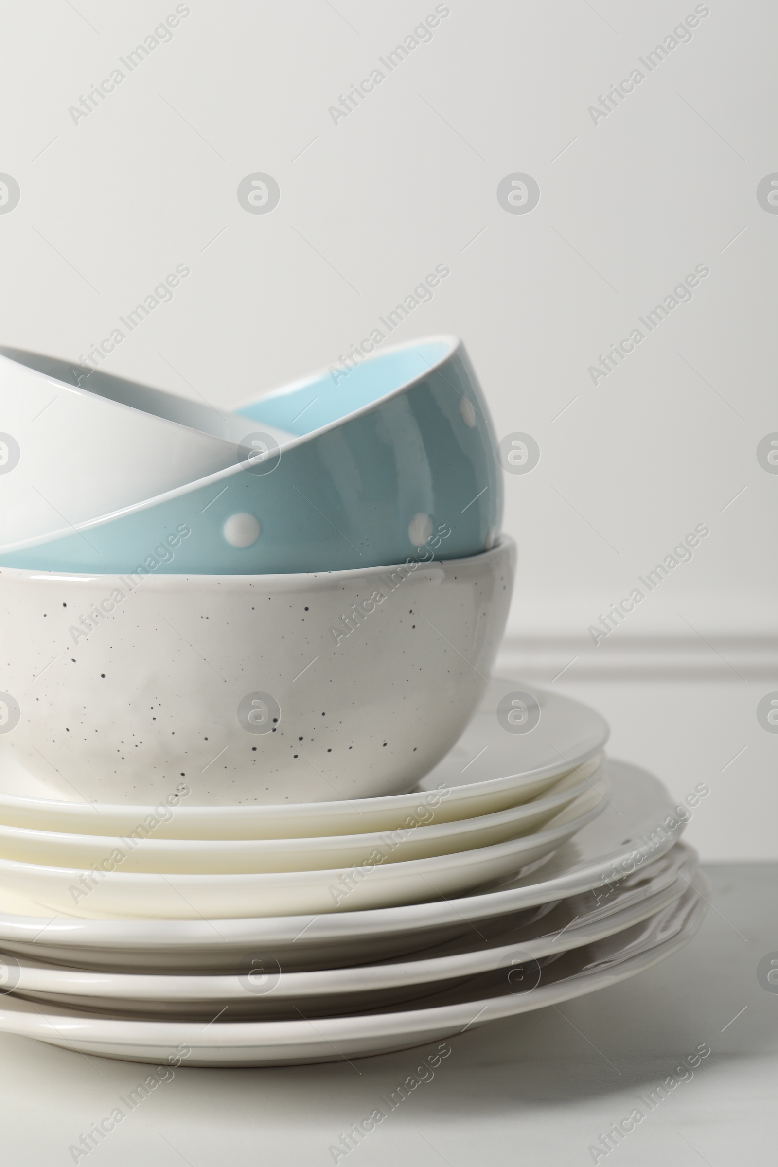 Photo of Stack of beautiful ceramic dishware on white table