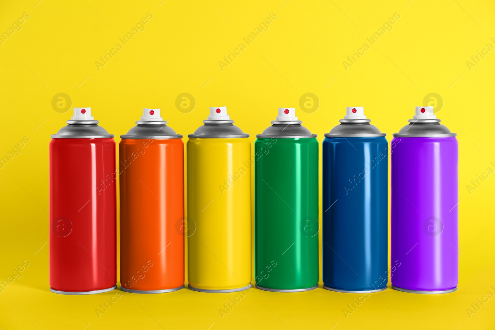 Photo of Colorful cans of spray paints on yellow background