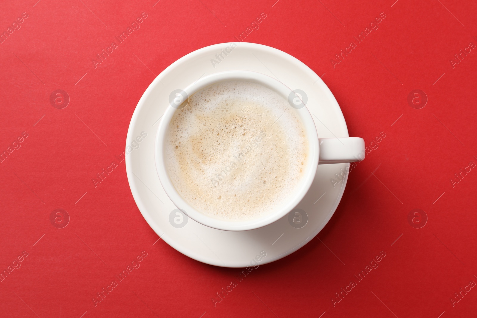 Photo of Cup of aromatic coffee on red background, top view