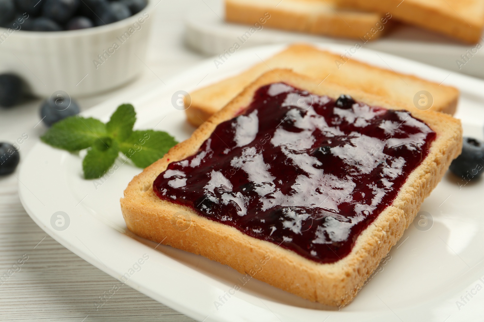 Photo of Toast with blueberry jam on white wooden table, closeup