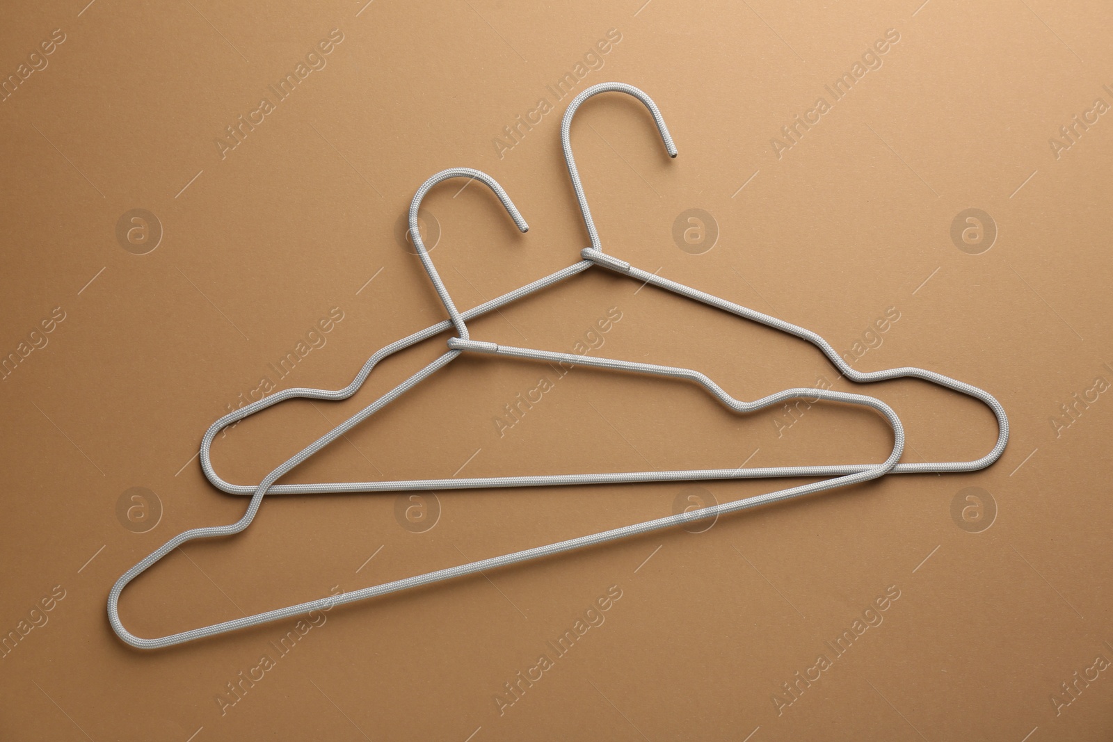 Photo of Empty hangers on brown background, top view