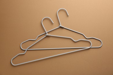 Empty hangers on brown background, top view