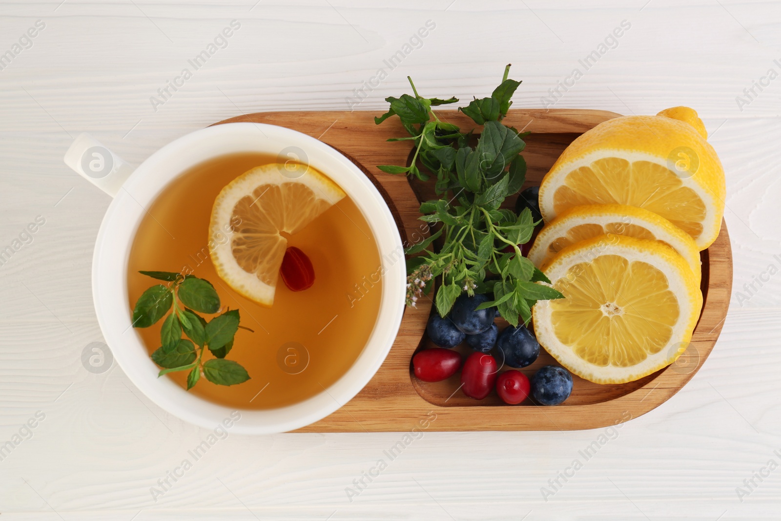 Photo of Cup with delicious immunity boosting tea and ingredients on white wooden table, top view