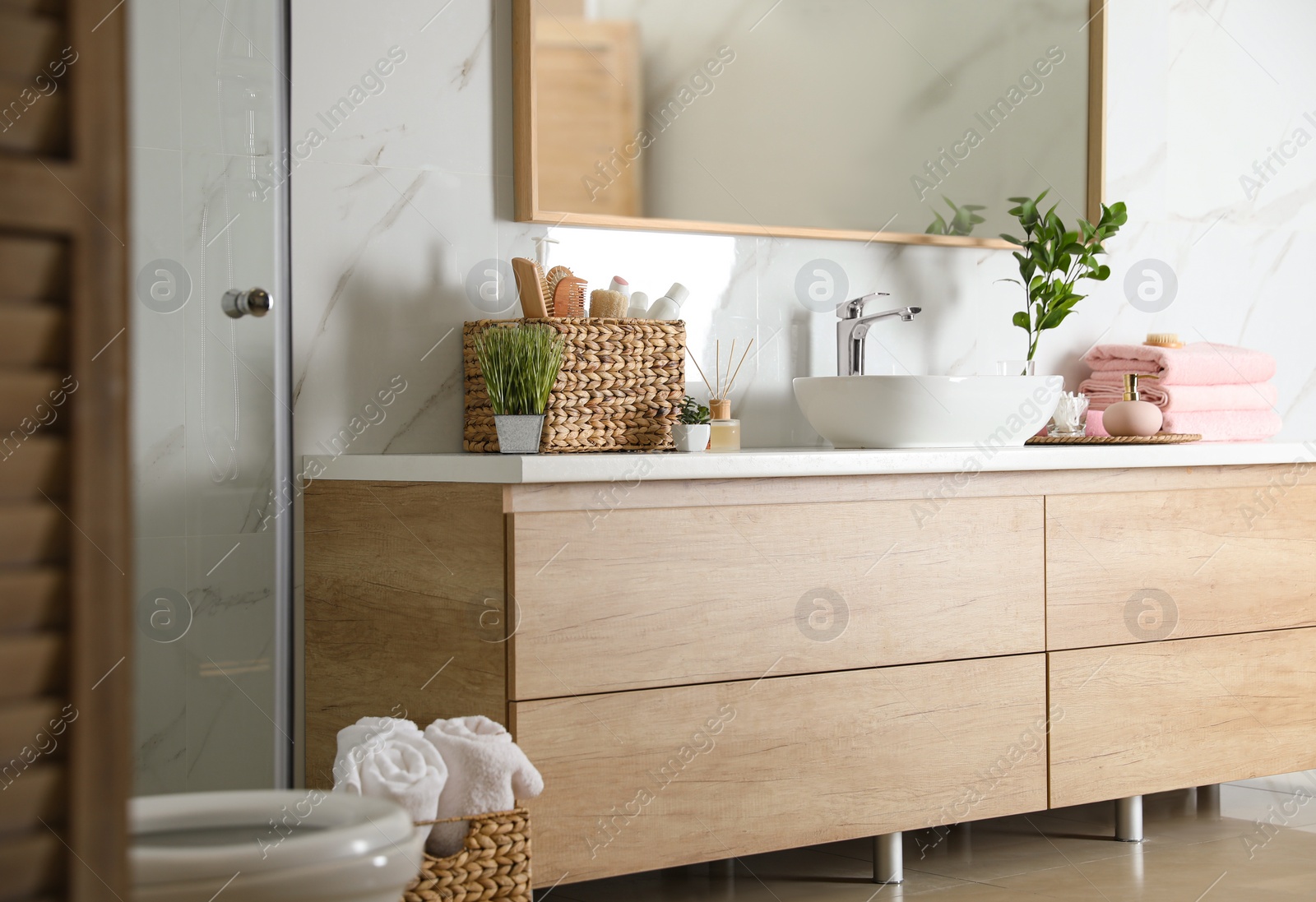 Photo of Elegant modern bathroom with wooden cabinet near marble wall