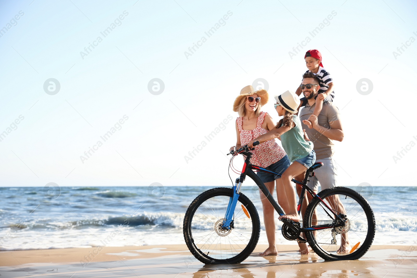 Photo of Happy family with bicycle on sandy beach near sea