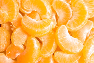 Pieces of ripe tangerines as background, top view