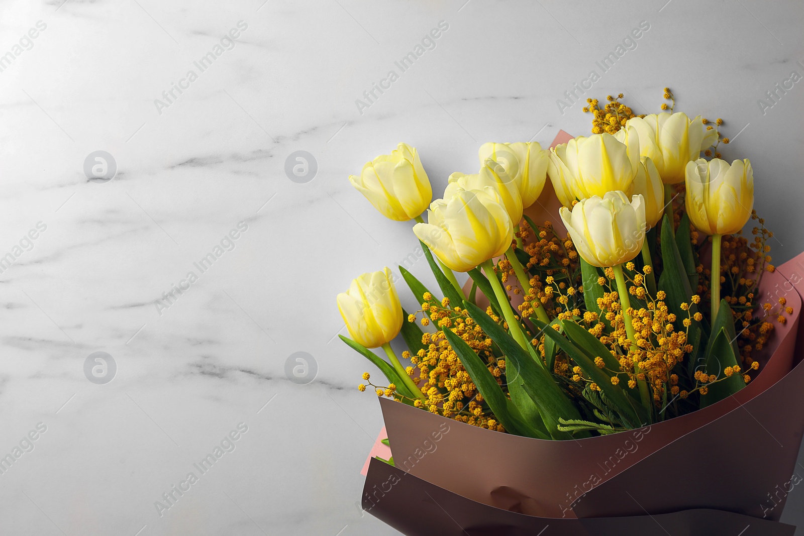 Photo of Bouquet with beautiful tulips and mimosa flowers on white marble table, top view. Space for text