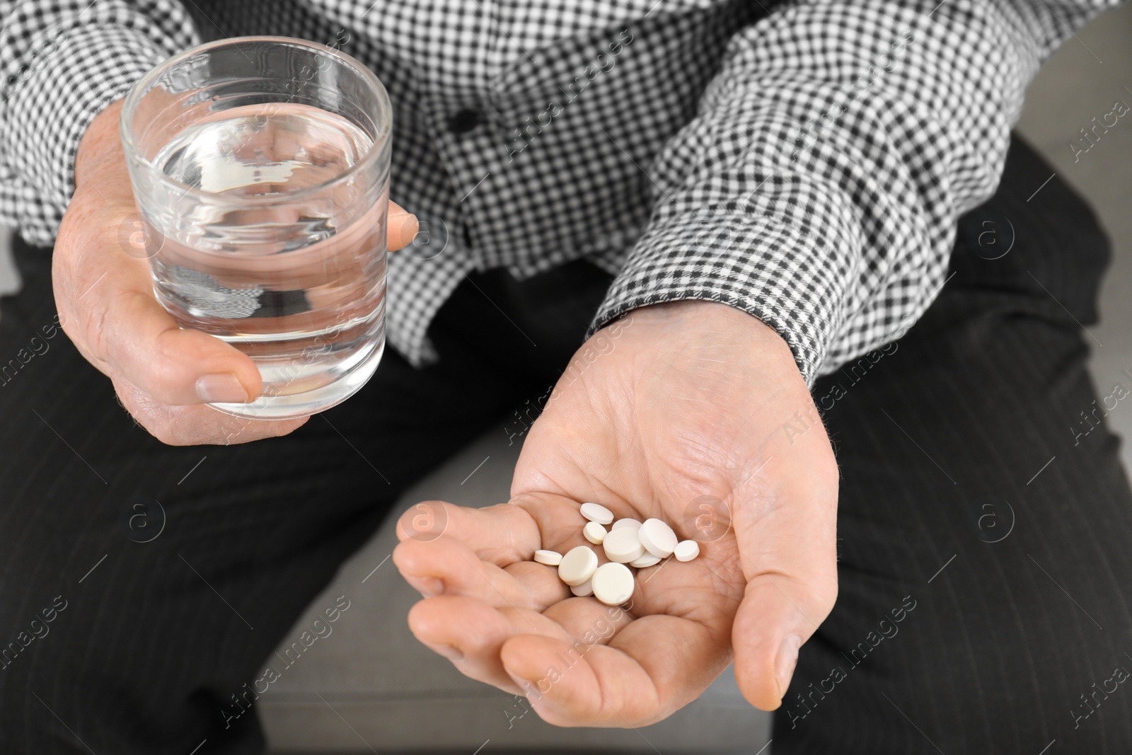 Photo of Senior man holding pills and glass of water, closeup