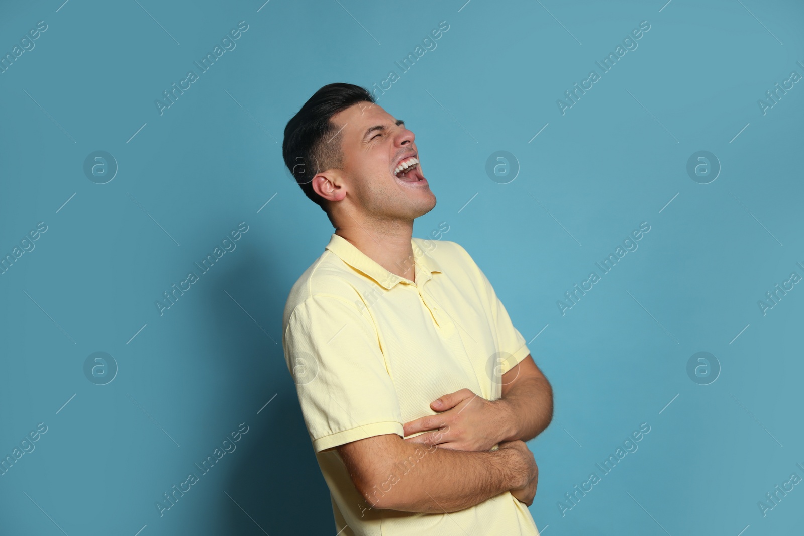 Photo of Handsome man laughing on light blue background. Funny joke