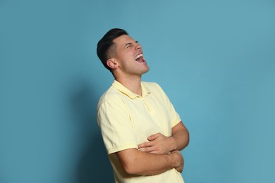 Photo of Handsome man laughing on light blue background. Funny joke