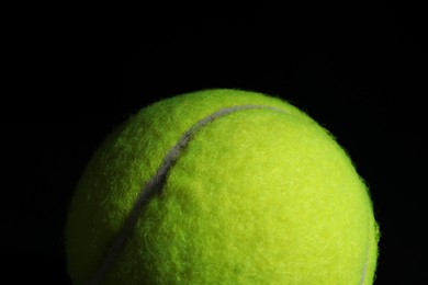 Photo of One tennis ball on black background, closeup