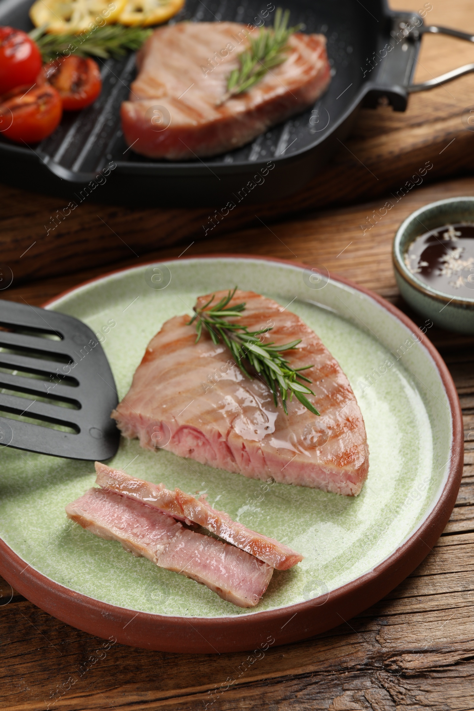 Photo of Delicious tuna steak with rosemary served on wooden table