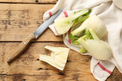 Fresh raw fennel bulbs and knife on wooden table, flat lay