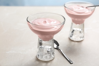 Photo of Glass dessert bowls with yummy yogurt on table