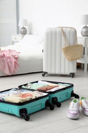Photo of Open suitcase packed for trip and shoes on floor in room