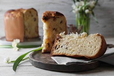 Delicious cut Panettone cake on light wooden table. Traditional Italian pastry