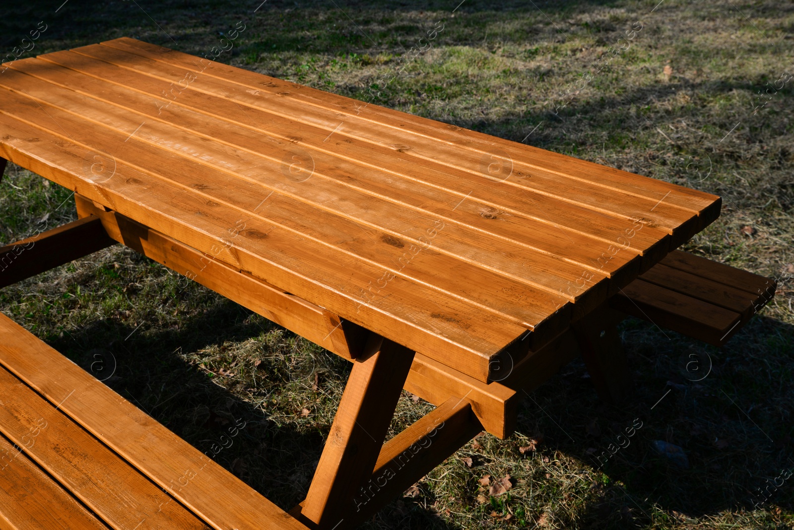 Photo of Empty wooden picnic table with benches in park on sunny day