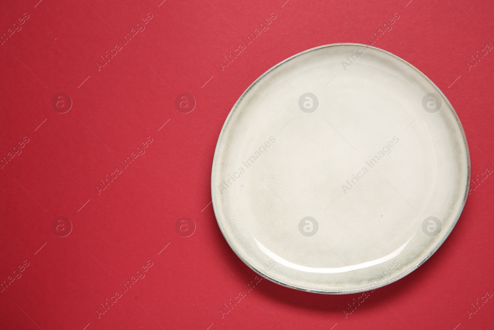 Photo of One ceramic plate on red background, top view. Space for text