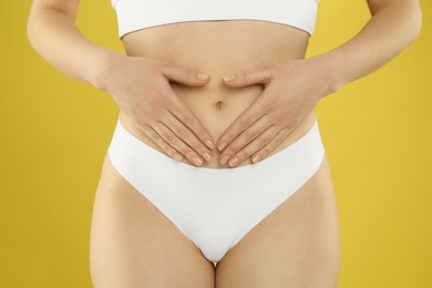 Gynecology. Woman in underwear on yellow background, closeup