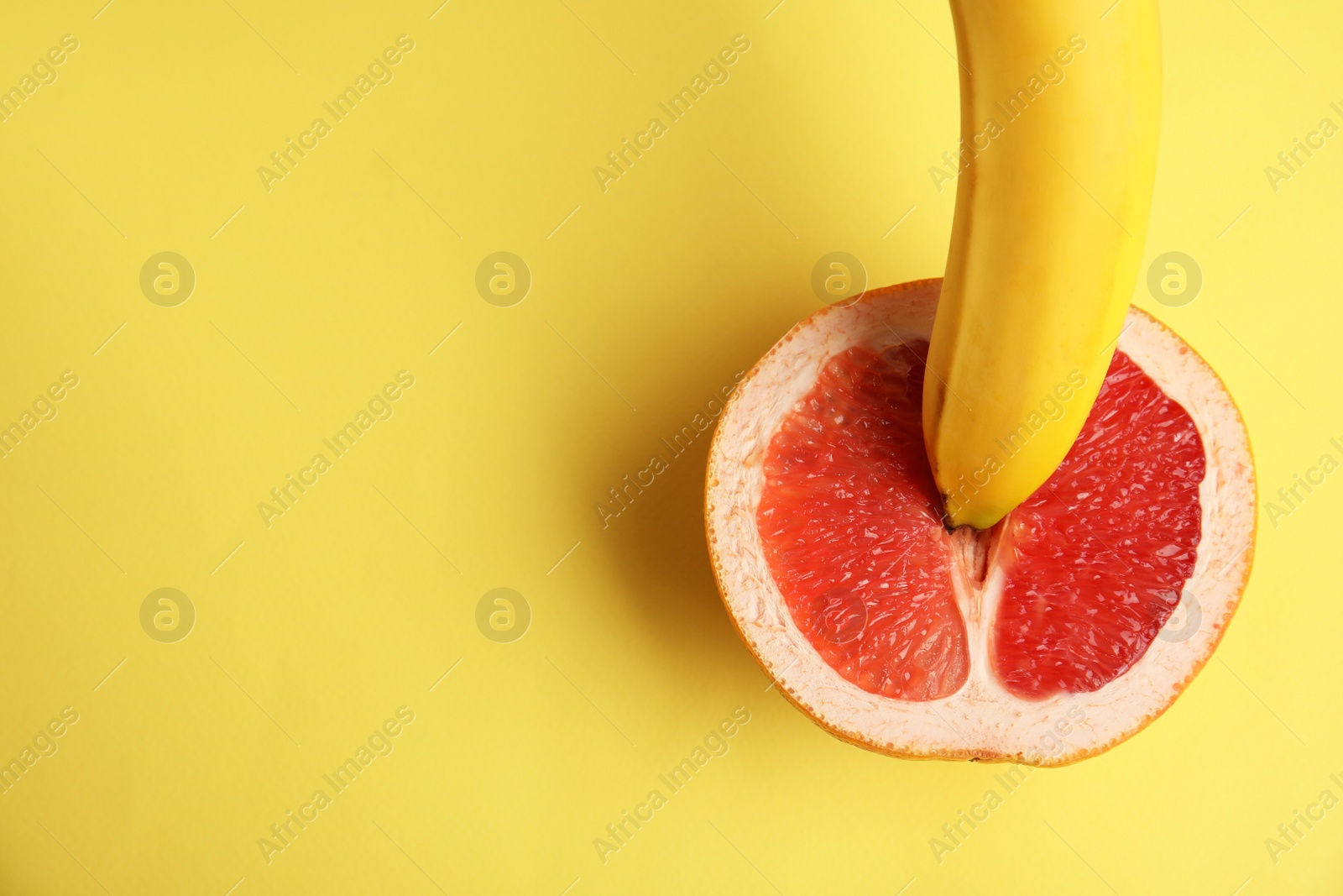 Photo of Flat lay composition with fresh banana and grapefruit on yellow background, space for text. Sex concept