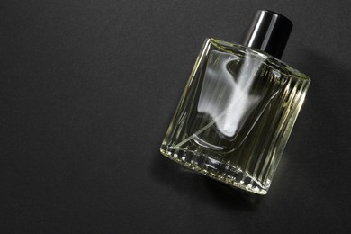 Photo of Luxury men`s perfume in bottle on black background, top view. Space for text