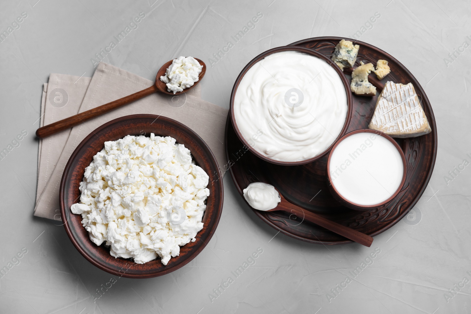 Photo of Clay dishware with fresh dairy products on grey table, flat lay