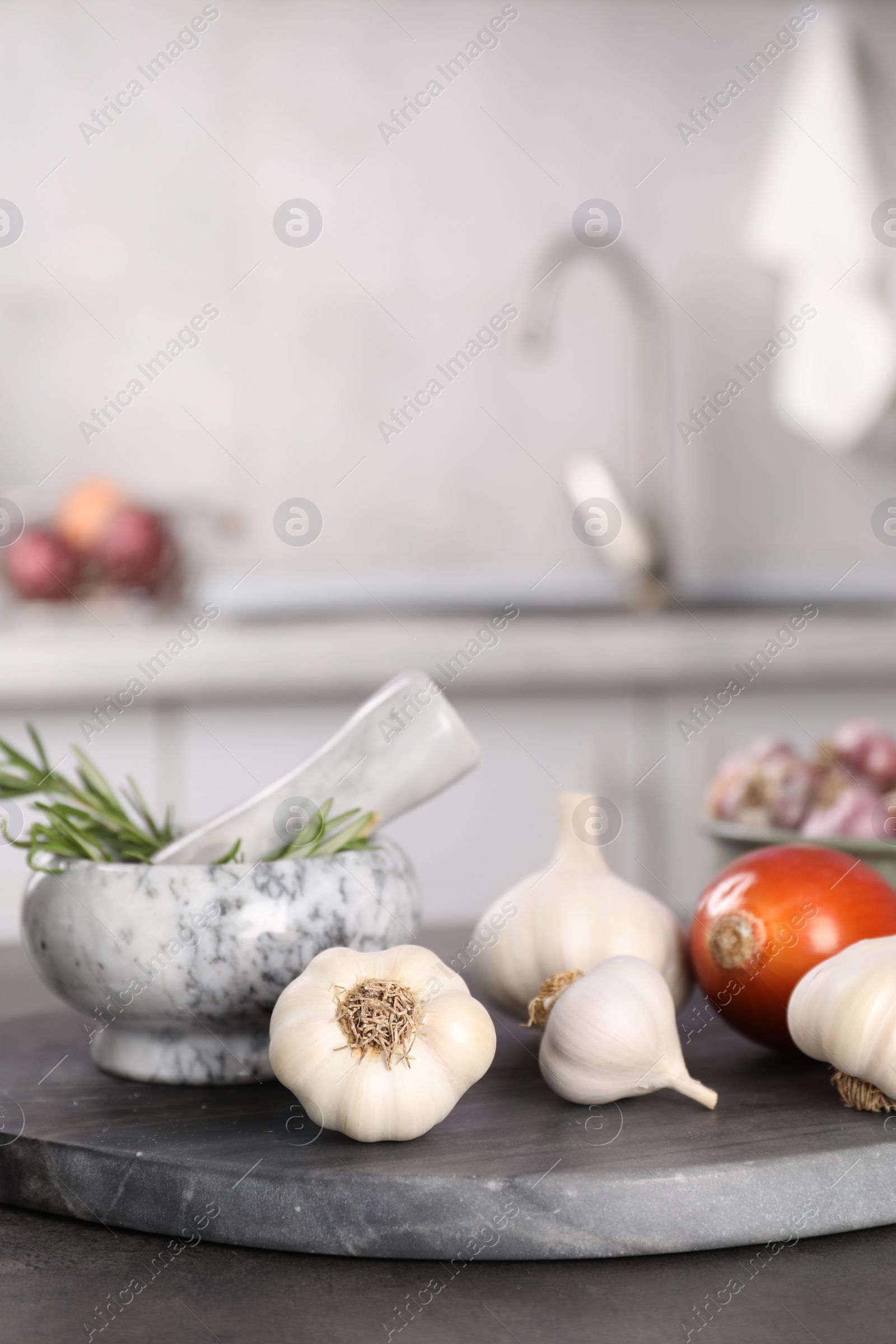 Photo of Fresh raw garlic, onion and rosemary on grey table, closeup. Space for text