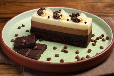 Tasty mousse cake and chocolate on plate, closeup
