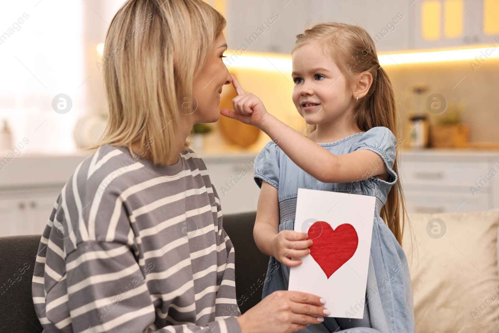 Photo of Little daughter congratulating her mom with greeting card at home. Happy Mother's Day