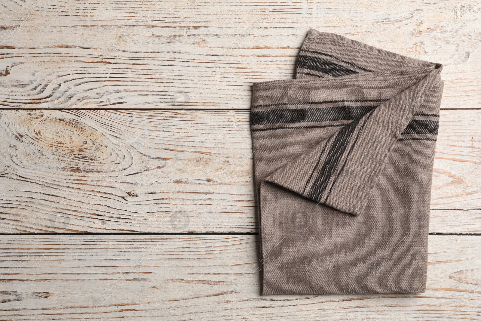 Photo of Fabric napkin on white wooden table, top view. Space for text