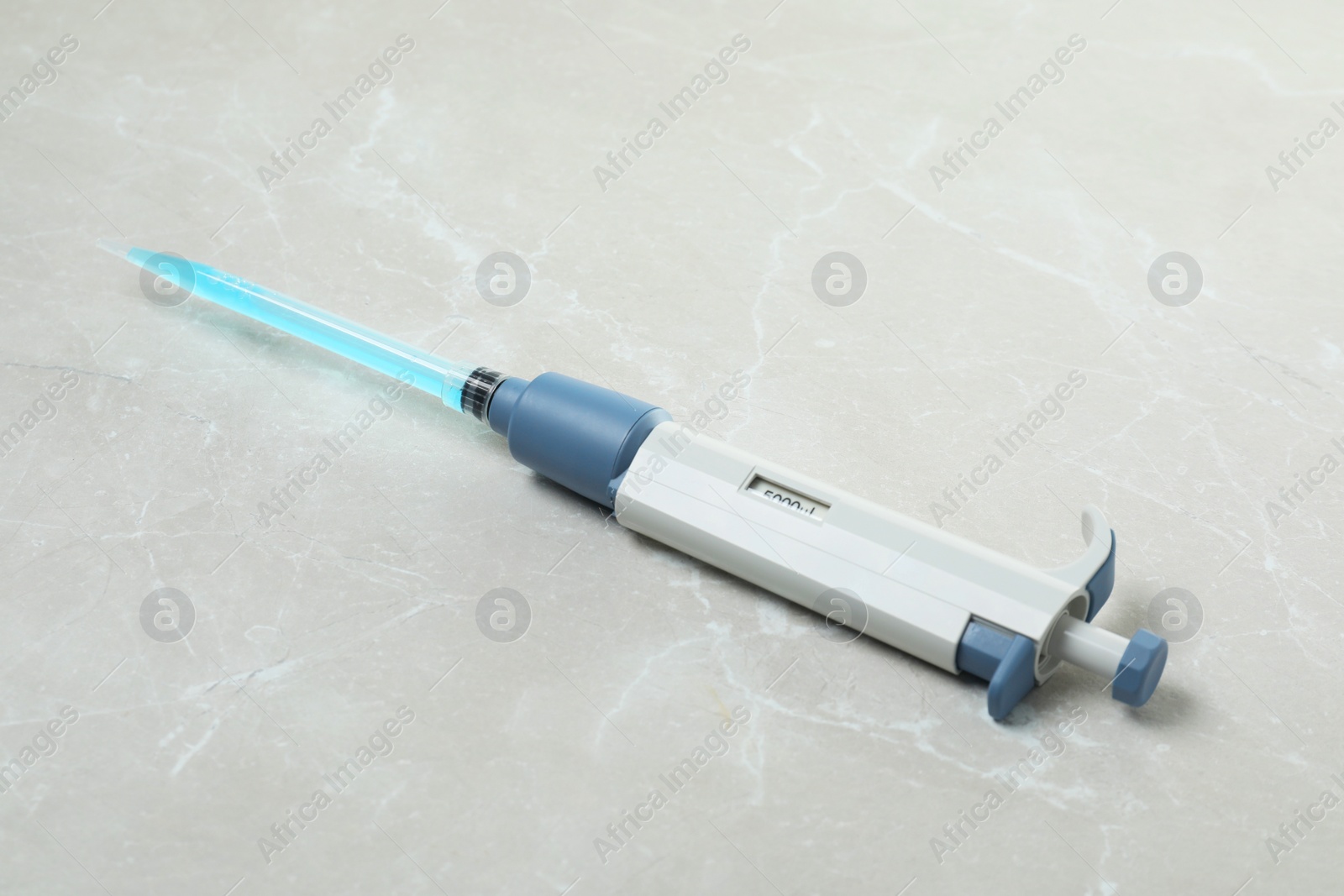 Photo of Laboratory analysis. Micropipette with liquid on light grey marble table