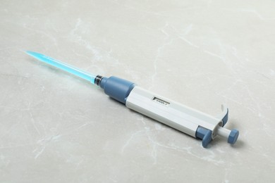 Photo of Laboratory analysis. Micropipette with liquid on light grey marble table