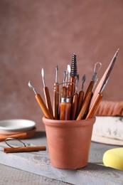 Photo of Clay and set of crafting tools on grey wooden table in workshop, closeup