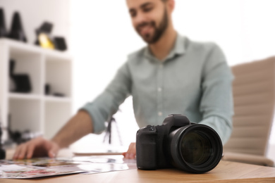 Photo of Professional photographer working at table in office, focus on camera