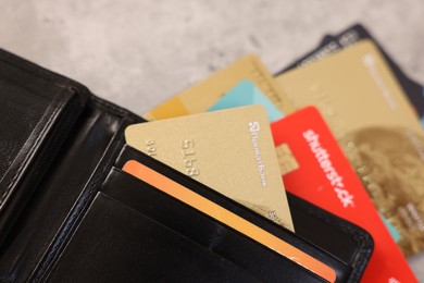 Many different credit cards and leather wallet on grey table, closeup