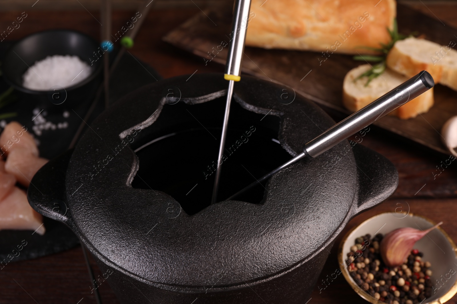 Photo of Fondue pot with forks on wooden table, closeup