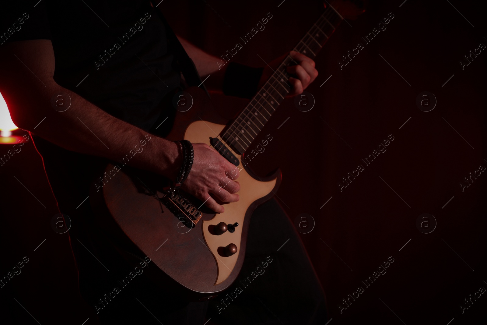 Photo of Man playing electric guitar on stage, closeup. Rock music