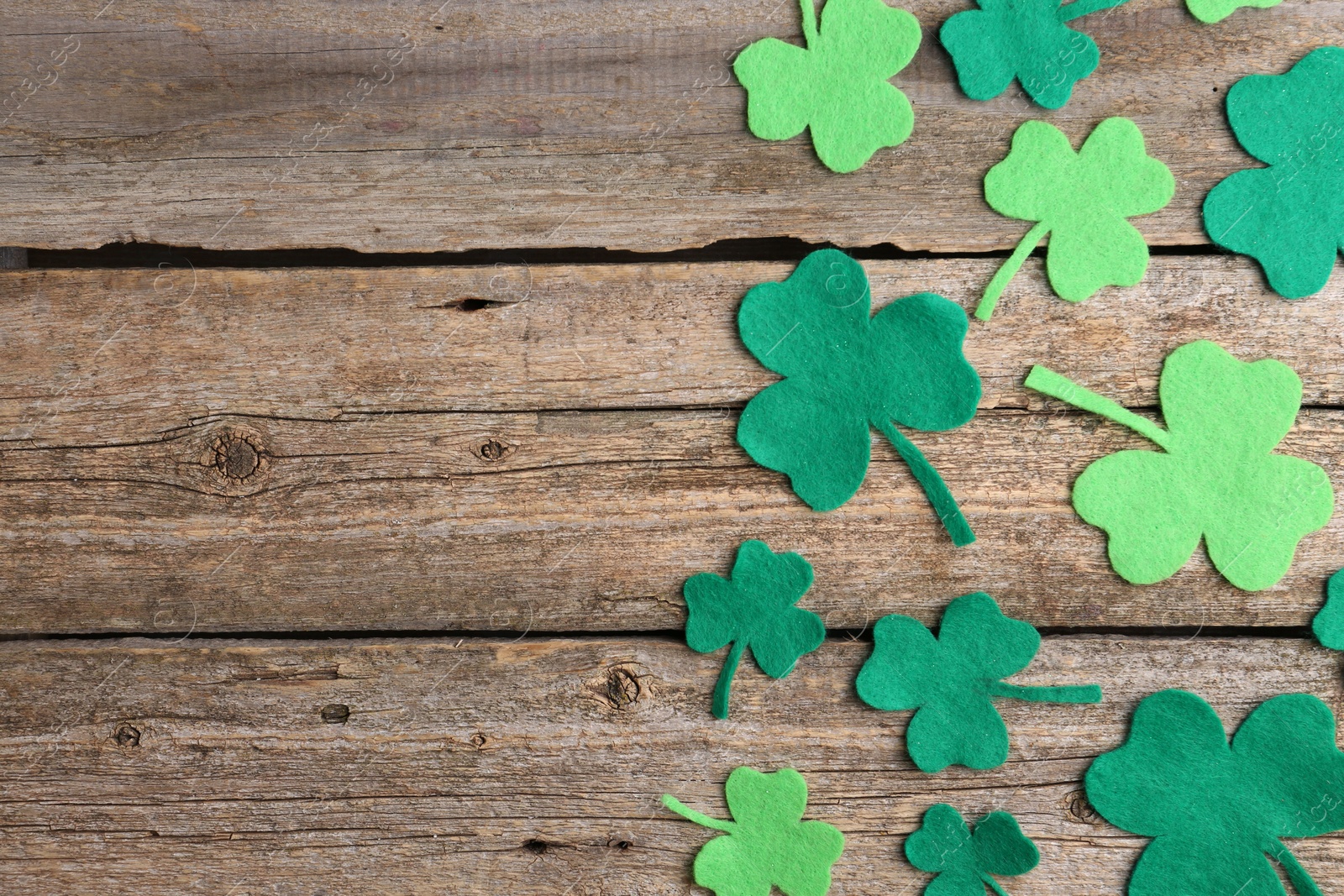 Photo of St. Patrick's day. Decorative clover leaves on wooden background, flat lay. Space for text