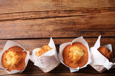 Photo of Delicious sweet muffins on wooden table, flat lay. Space for text