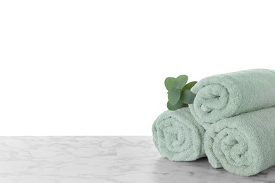Photo of Fresh towels and eucalyptus branch on marble table against white background. Space for text