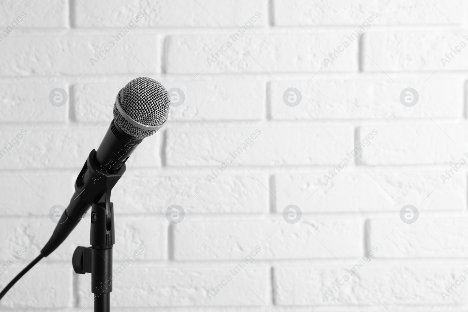 Photo of Modern microphone near brick wall. Space for text