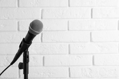 Photo of Modern microphone near brick wall. Space for text