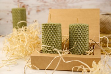Photo of Stylish elegant beeswax candles and twine on white wooden table